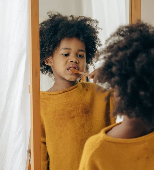 Kid with toothbrush in mirror